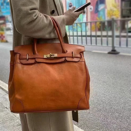 Genuine Leather Tote Bag Women in brown, held by a person standing on the street with a smartphone.