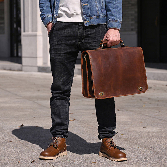 Vintage Leather Briefcase 15.4in Dual Compartment Bag For Men held by a man in casual attire outdoors.