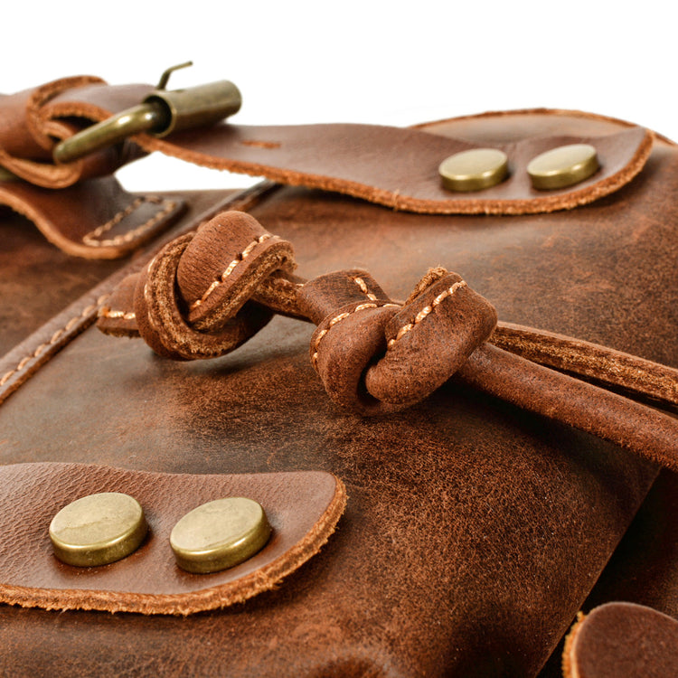 Close-up of a brown leather backpack featuring durable materials and stylish hardware details.