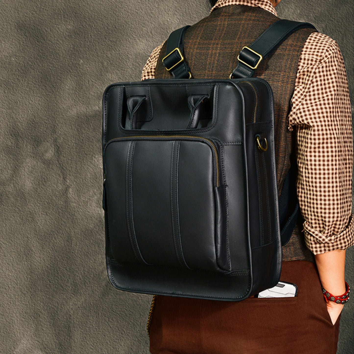 Black leather laptop bag worn as a backpack, featuring adjustable straps and stylish design.