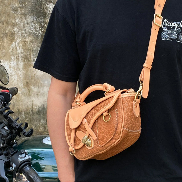 Saddle Bag,Leather Crossbody Bags,Saddle Bag Leather,8.7in hanging from a person with a motorcycle in the background.