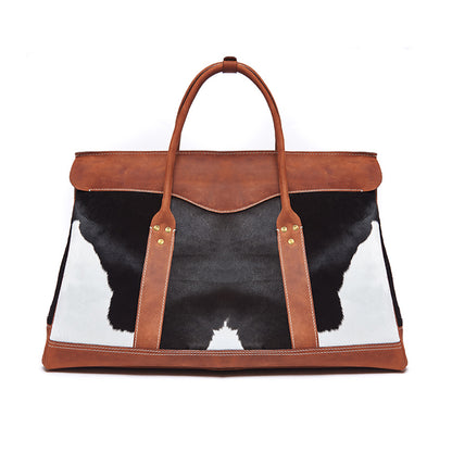 Bag with cow print and brown leather straps on a white background