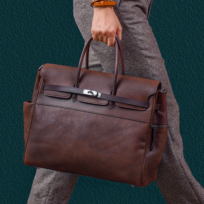 Man carrying a stylish brown leather tote work bag, featuring two handles and a sleek design.