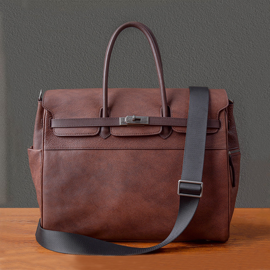 Men's leather work bag in brown with two handles and a removable shoulder strap on wooden surface.