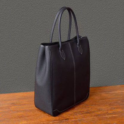 Black large vertical tote bag made of top-grain leather with handles, perfect for laptops and everyday use.