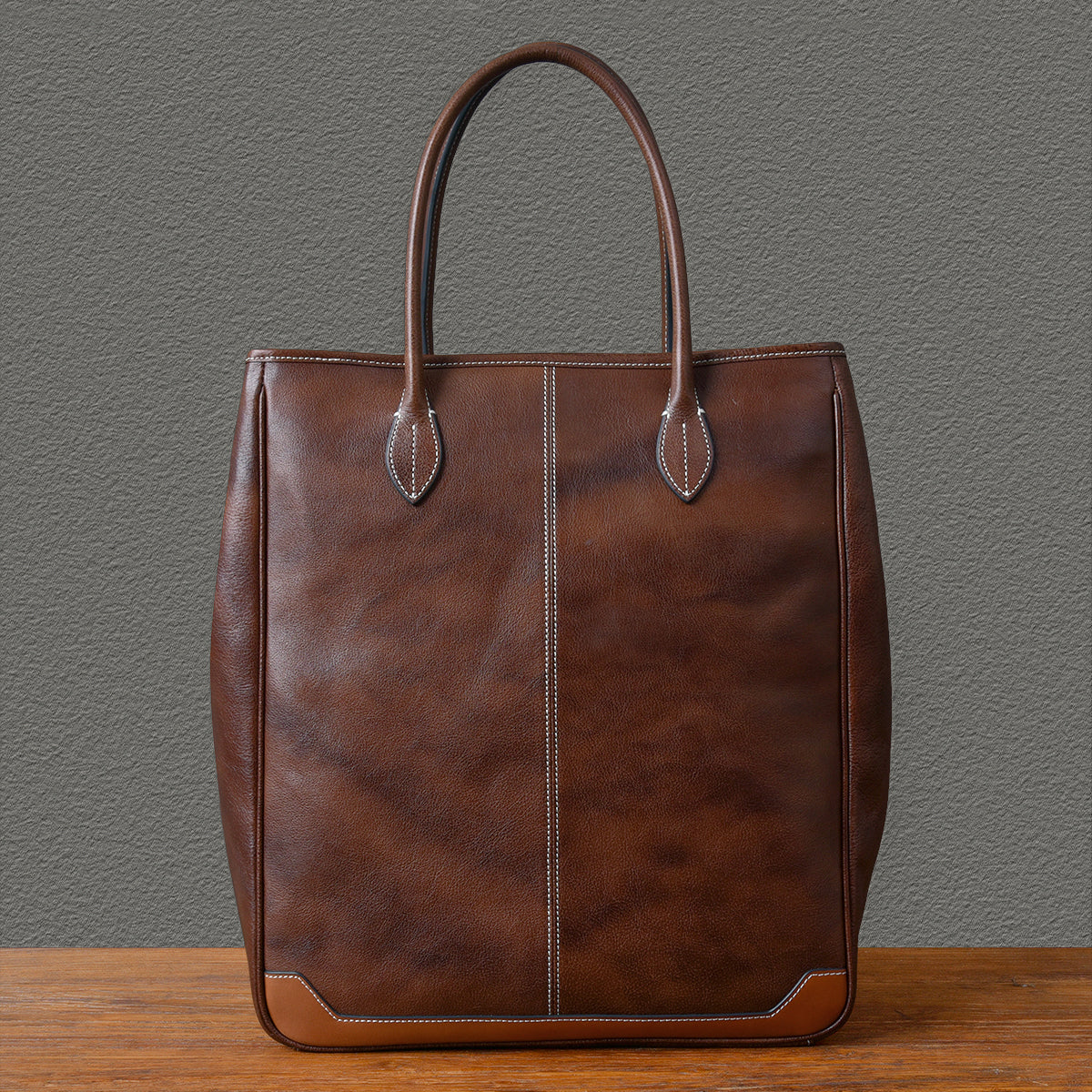 Large vertical cowhide tote bag in brown top-grain leather, unisex design, height 16.5 inches, stylish and durable.