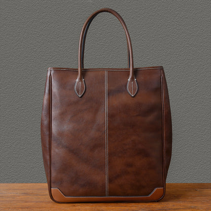 Large vertical cowhide tote bag in brown top-grain leather, unisex design, height 16.5 inches, stylish and durable.
