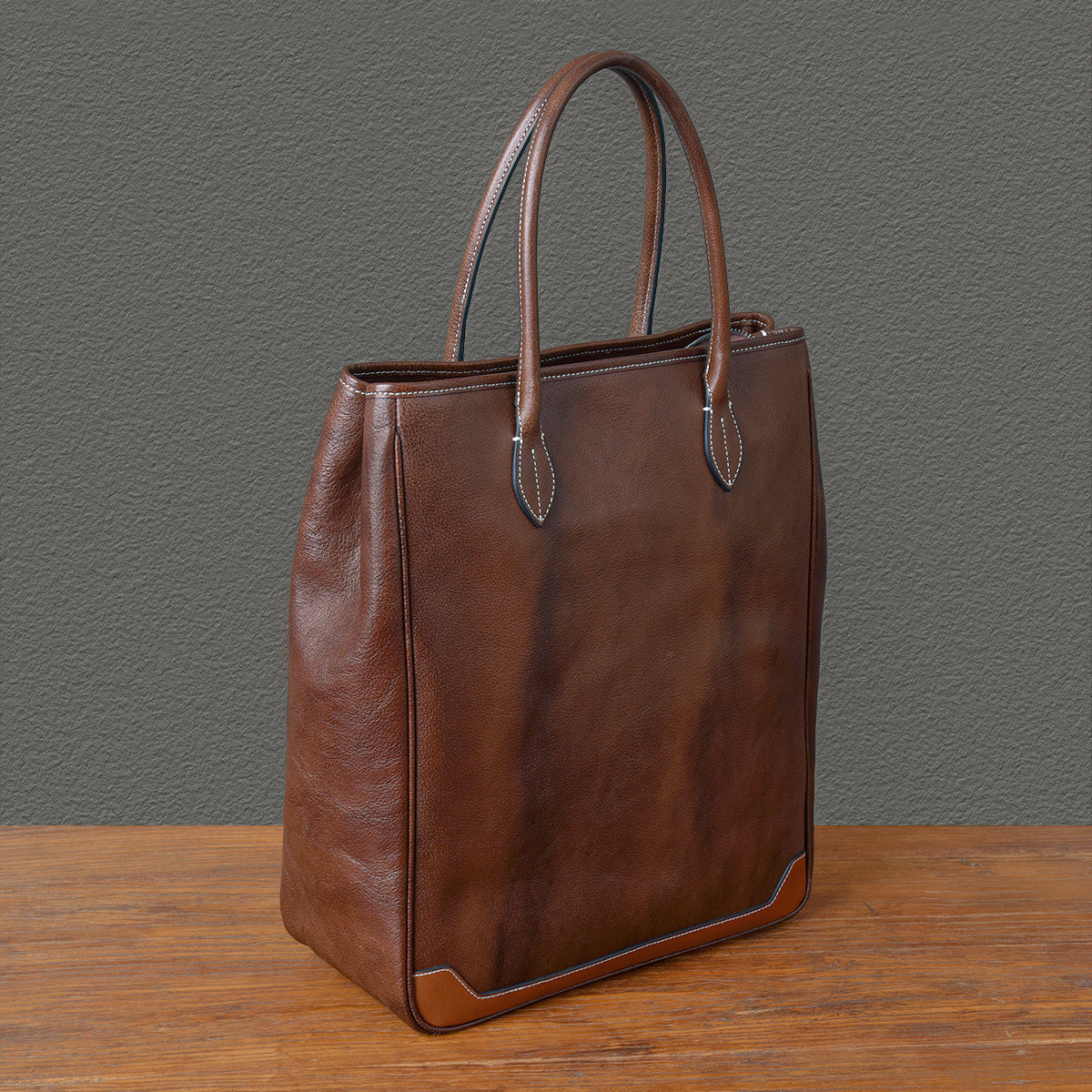 Brown large vertical cowhide tote bag with top-grain leather, perfect for laptops and everyday use.