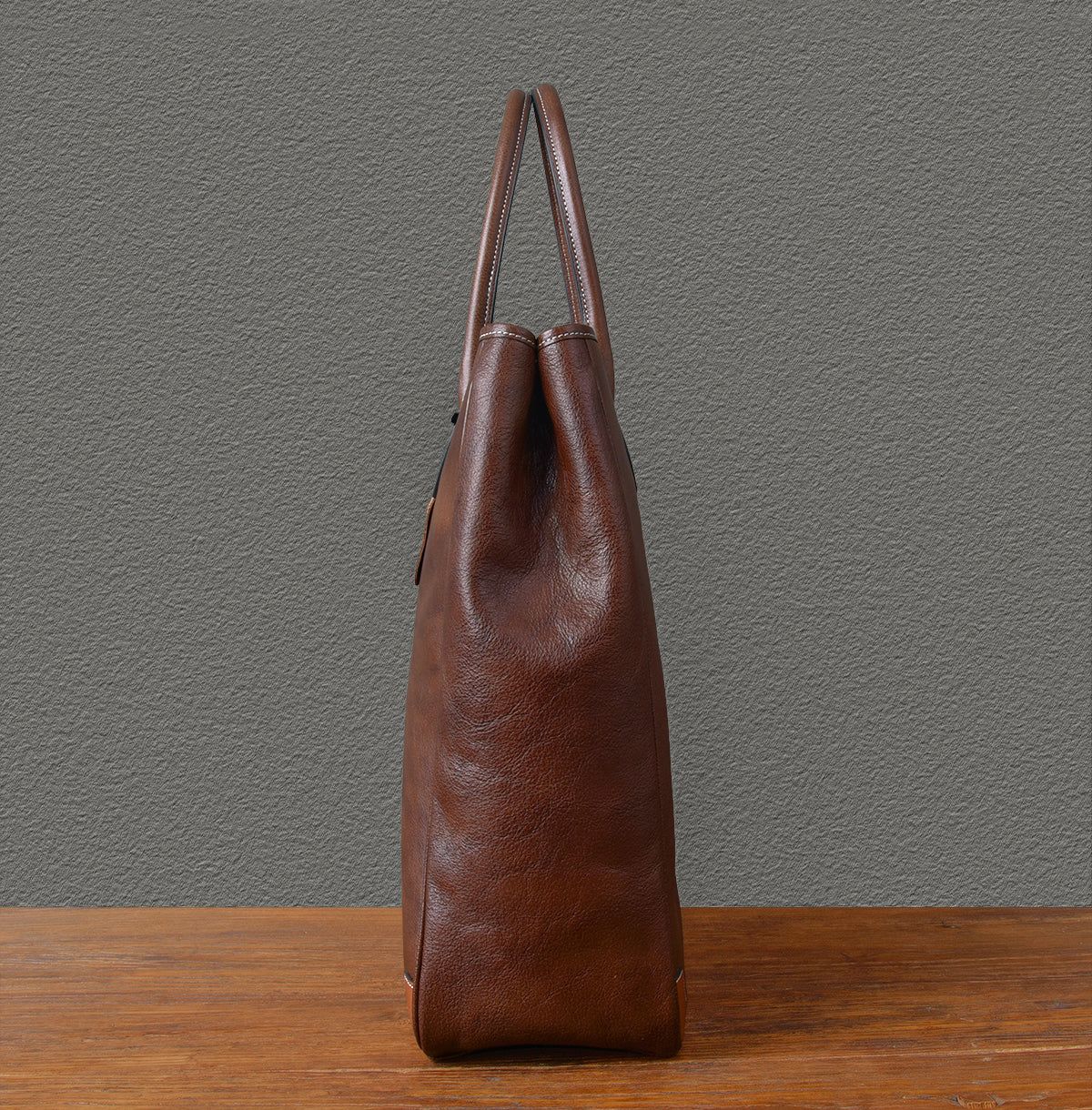 Large vertical cowhide tote bag showing side view, handcrafted from top-grain leather in brown color.