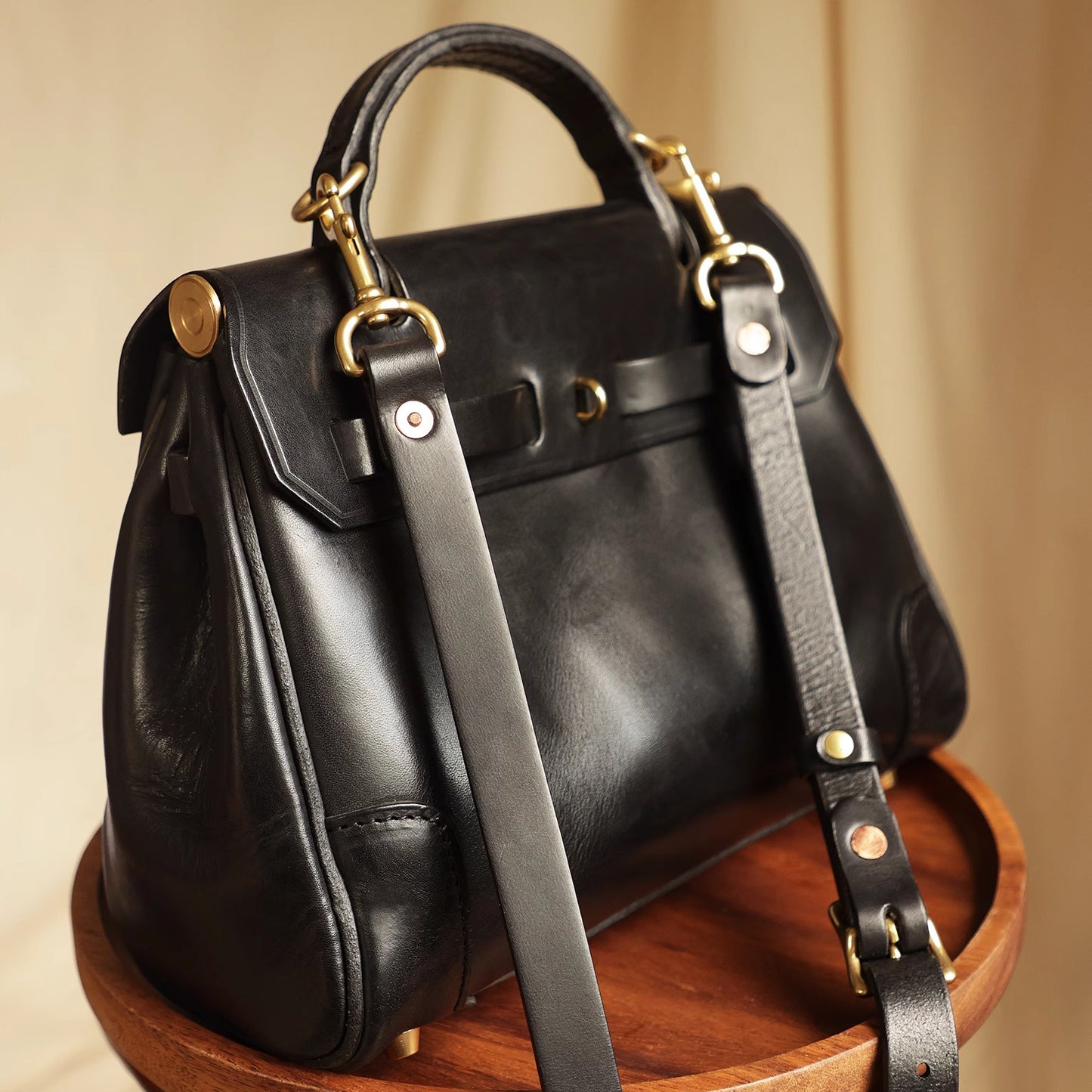 Classic Leather Bag, black leather crossbody bag displayed on a wooden table, showcasing elegant design and craftsmanship.