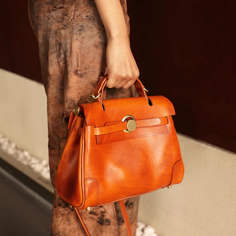 Classic Leather Bag in vibrant orange held by a woman, showcasing a stylish leather crossbody design.