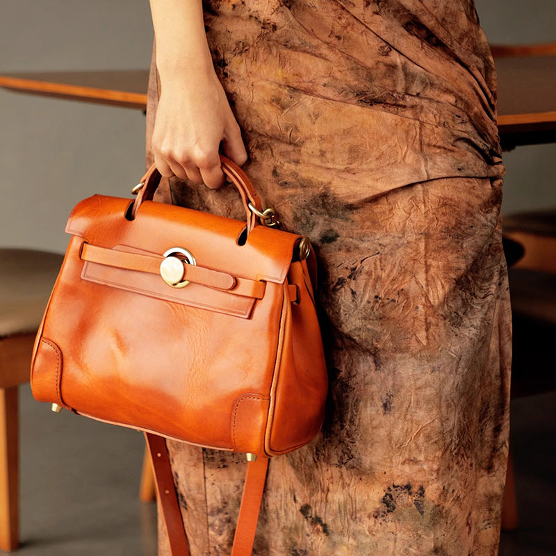 Classic Leather Bag in rich orange color, held by a person, showcasing a stylish design and elegant craftsmanship.