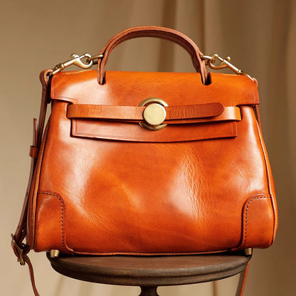 Classic Leather Bag in rich orange color, featuring a top handle and detachable strap on a wooden table.