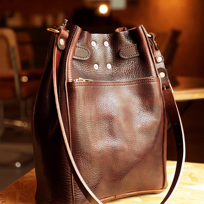 Classic Italian Leather Bucket Bag Women in dark brown color with shoulder strap and exterior pocket.