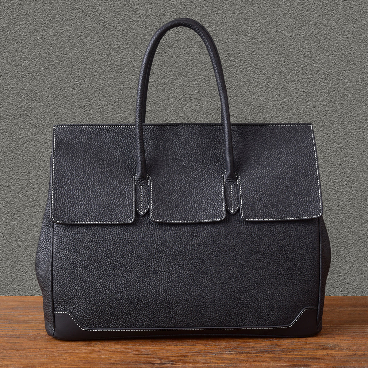 Elegant black leather work bag with structured design and top handles, perfect for professional use.