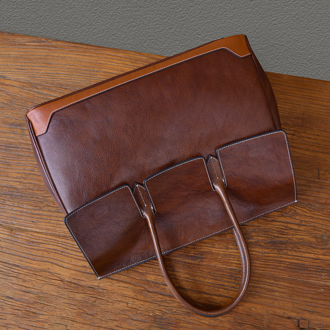 Top-grain leather large brown business tote bag with two open pockets and sturdy handles.