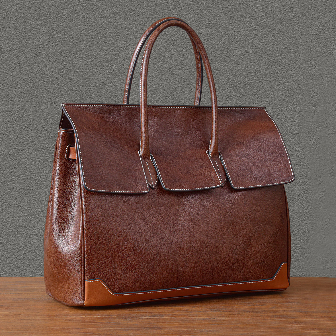 Large top-grain leather business tote bag in brown with double handles and stylish flap design.