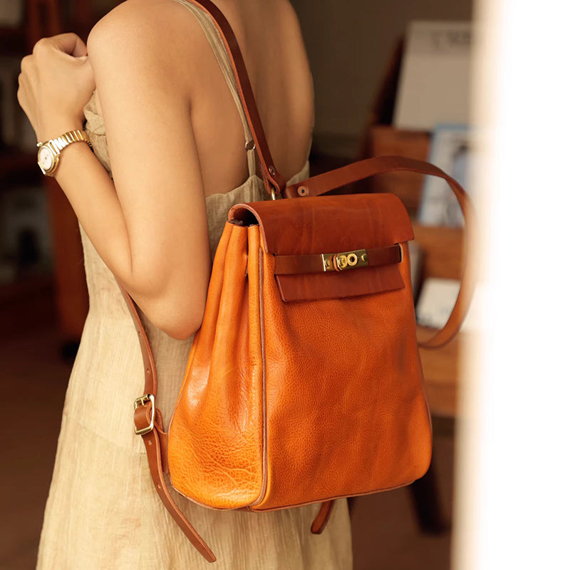 Leather Backpack Women in vibrant orange color worn on the back of a woman, showcasing stylish design and functionality.