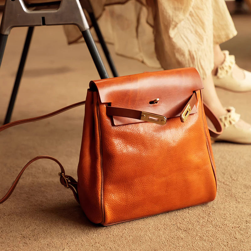 Leather Backpack Women in a stylish orange color, featuring a roll-top design and elegant hardware accents.