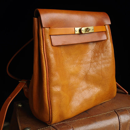 Vegetable tanned leather backpack women small rucksack in warm orange color with a sleek design and brass details.