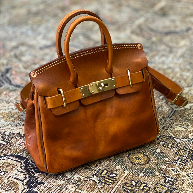 Handcrafted Italian Leather Crossbody Bag Women in rich brown with gold clasp detail on intricate background