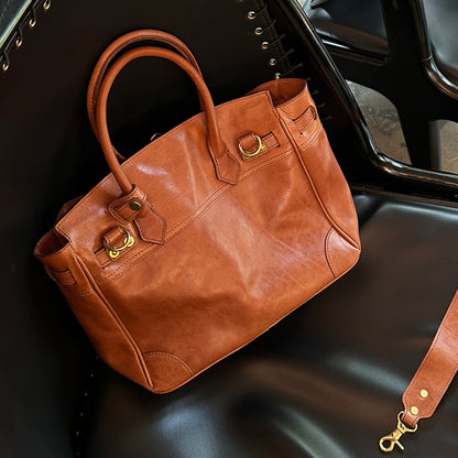 Genuine Leather Tote Bag Women placed on a black chair, showcasing its stylish design and large work bag features.