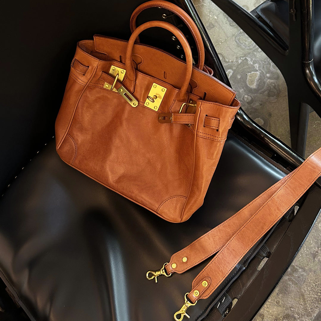 Genuine Leather Tote Bag Women in brown with gold hardware resting on a black leather seat.