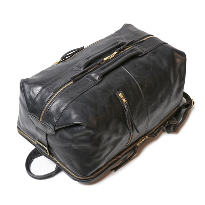 Top view of an 18-inch black full-grain leather laptop backpack with gold zippers, reinforced handles, and leather straps.