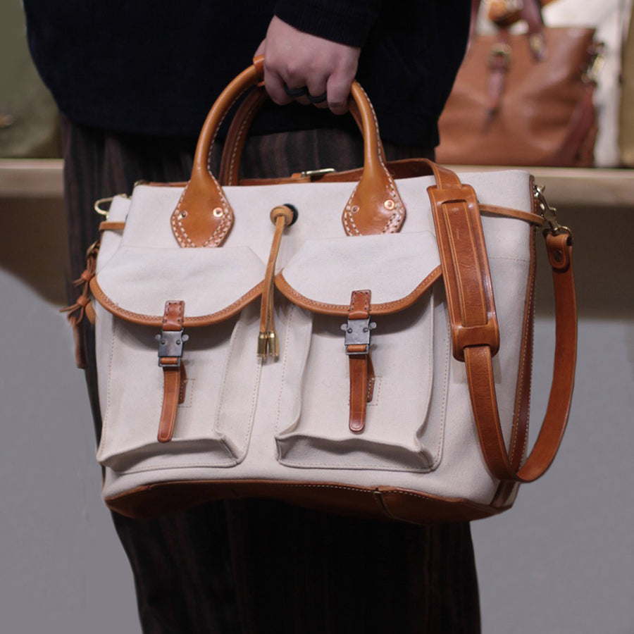 Large Canvas Leather Tote Bag with pockets and shoulder strap being held by a person.