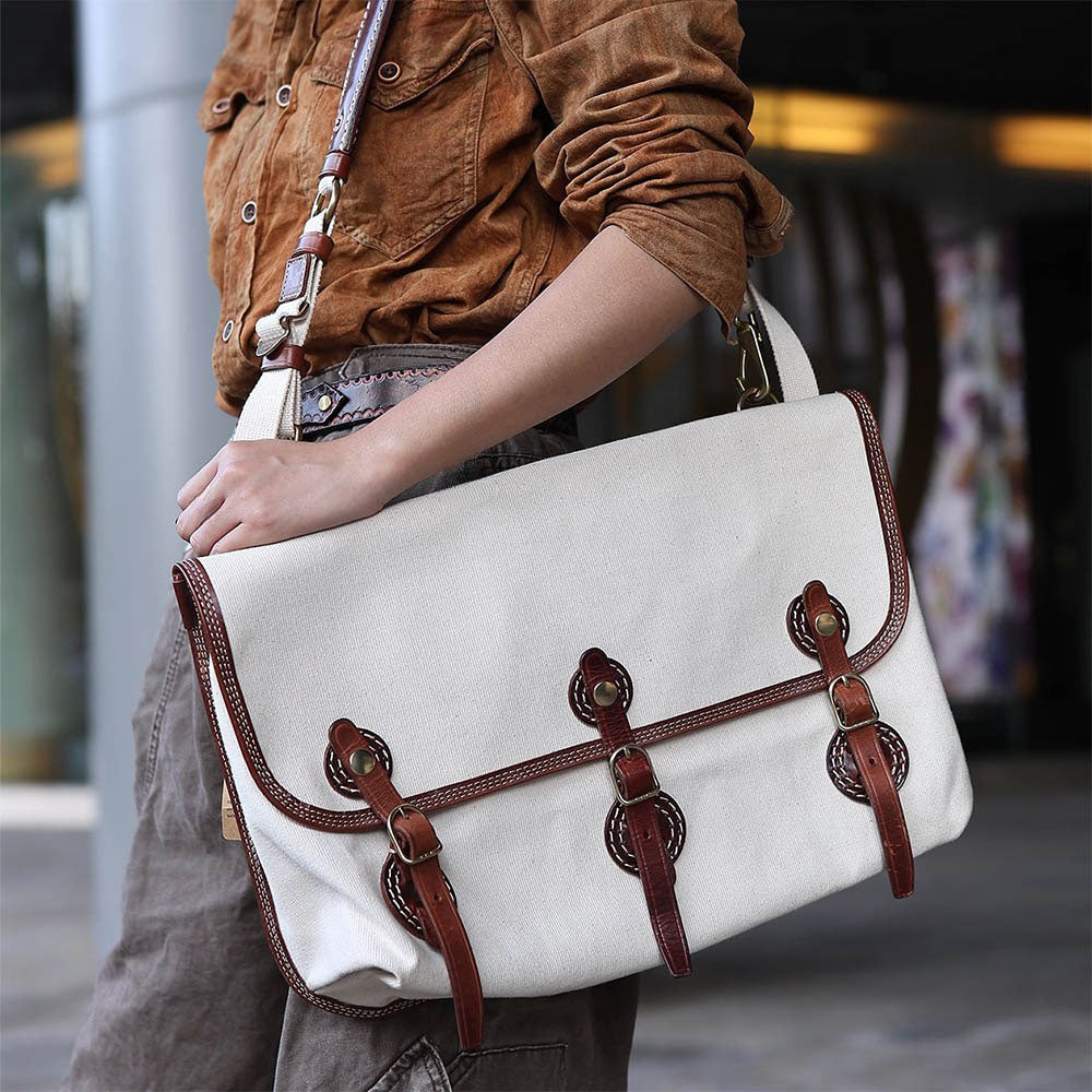 Canvas Messenger Bag Italian Leather 16.5in Laptop Bag displayed by a model with stylish outfit outdoors.