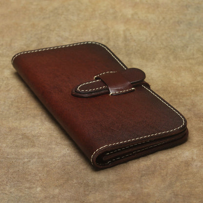 Full Grain Leather Long Wallet Hand Stitched Strap Clasp Clutch in dark brown color on textured background.
