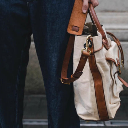 Person holding a Large Canvas Leather Tote Bag with brown straps, showcasing its vintage design and style.