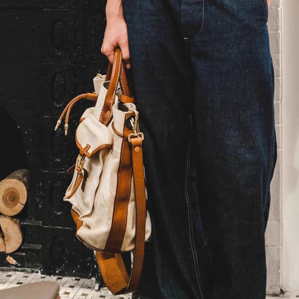 Large Canvas Leather Tote Bag held by a person, showcasing vintage design and adjustable shoulder strap.