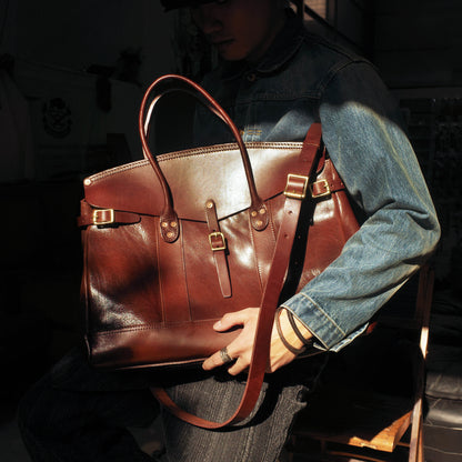 Person holding an Italian Leather Travel Bag in a stylish setting, featuring straps and a sleek design.