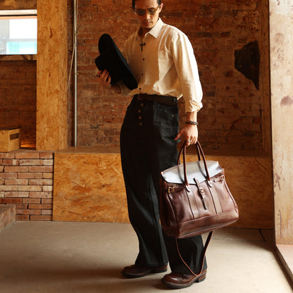 Man in stylish outfit holding a hat and Italian Leather Travel Bag, showcasing the bag's elegance and functionality.