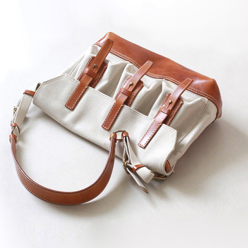 Canvas Leather Messenger Bag featuring three front pockets and a sleek design with a brown leather strap.