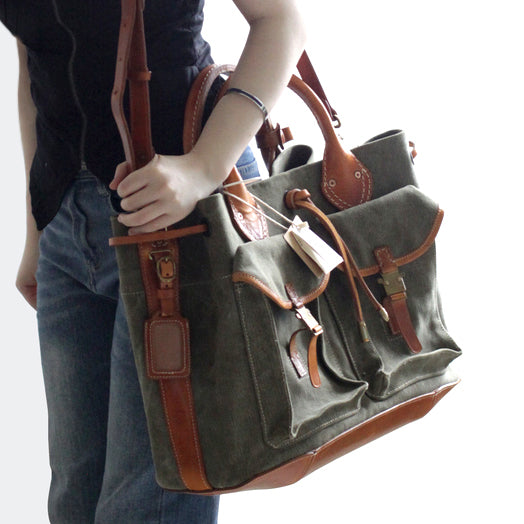 Person holding a Large Canvas Leather Tote Bag with pockets, showcasing its vintage crossbody style.