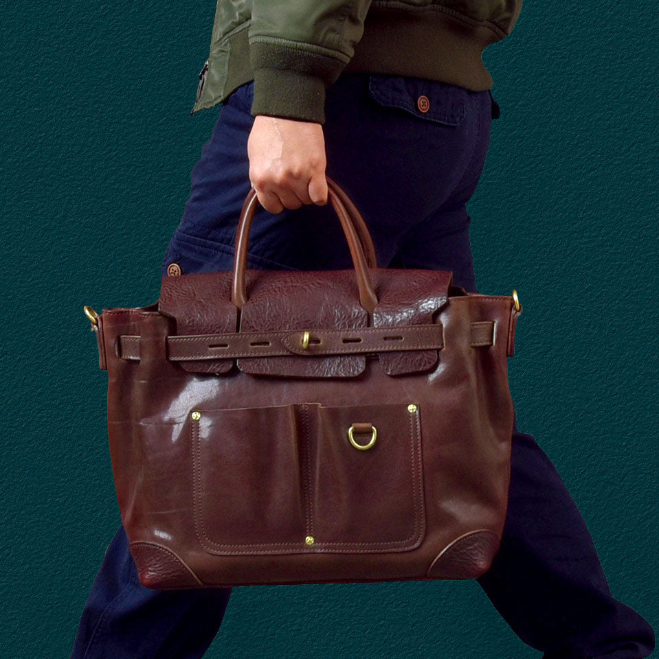 A person carrying a Vegetable-Tanned Leather Work Tote Laptop Briefcase Bag in rich brown leather.