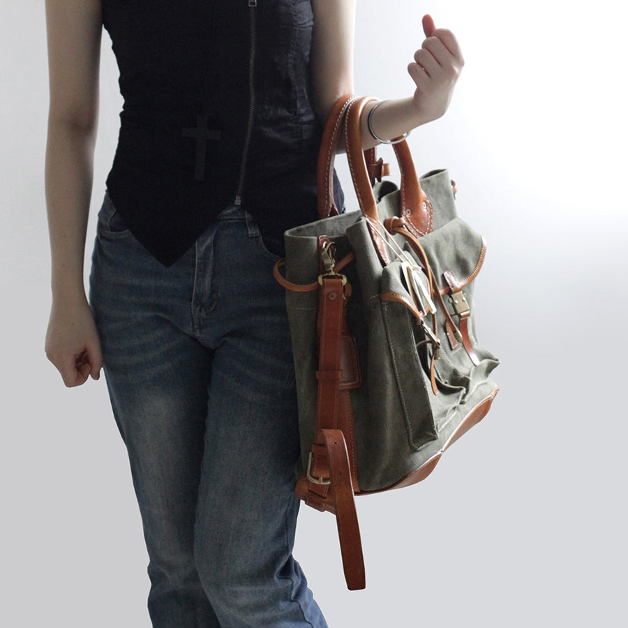 Person holding a Large Canvas Leather Tote Bag featuring pockets and crossbody strap.