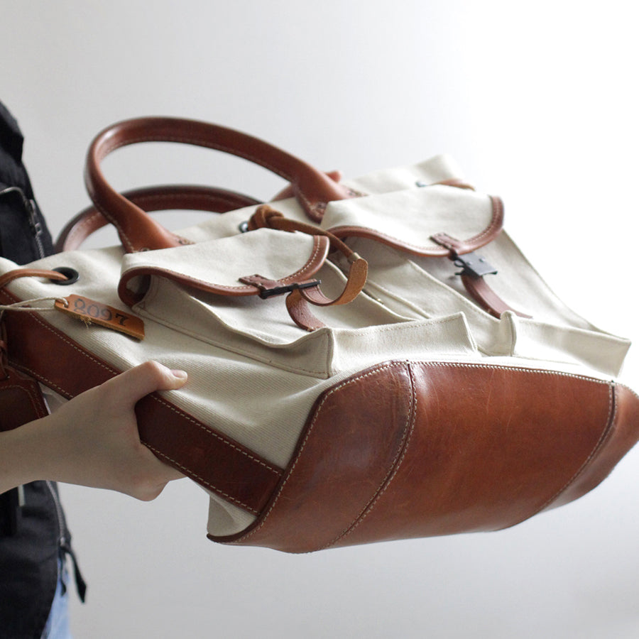 Large Canvas Leather Tote Bag in hand, featuring vintage design and multiple pockets for functionality.