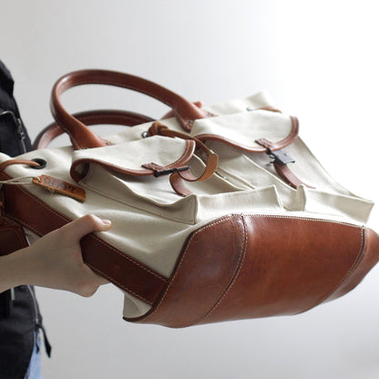 Large Canvas Leather Tote Bag in hand, featuring vintage design and multiple pockets for functionality.