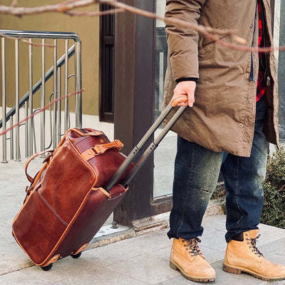 Man holding a Handmade Leather Travel Bag With Wheels, 23.6in rolling duffel luggage, outdoors.