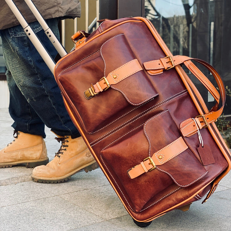 Handmade Leather Travel Bag With Wheels being rolled on pavement, showcasing its sturdy design and beautiful leather finish.