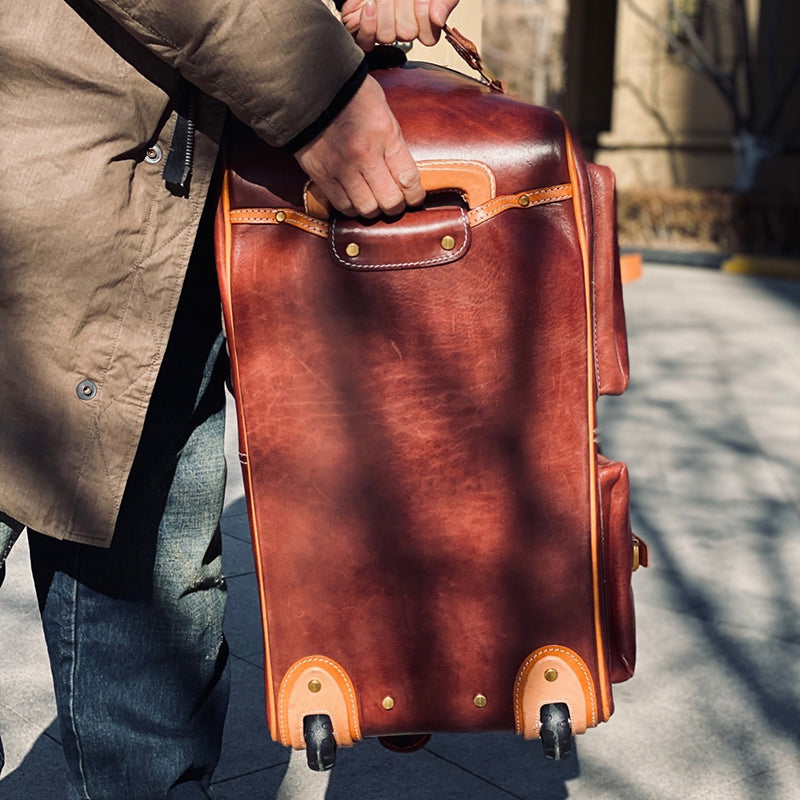 Handmade Leather Travel Bag With Wheels being carried in brown leather, showcasing its durability and style.